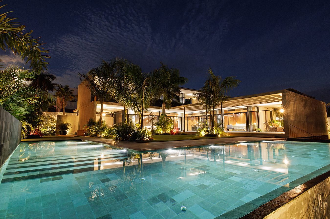 Villa residencial premium con piscina iluminada al anochecer