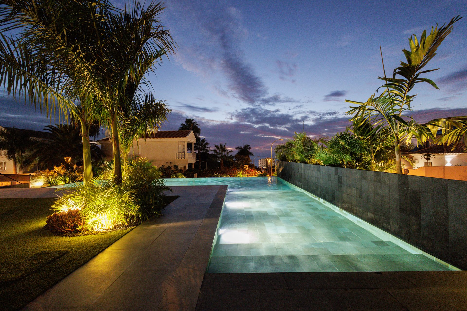 Piscina desbordante de Villa Bali iluminada de noche entre palmeras, Costa Adeje