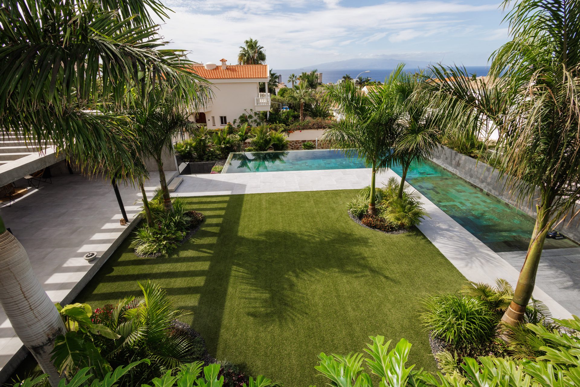 Jardín de Villa Bali con palmeras y la piscina desbordante al fondo, en Playa Paraíso (Costa Adeje)